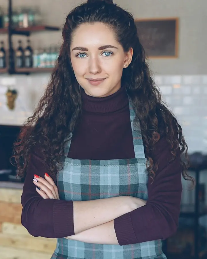 Inhaberin steht lächelnd in ihrem Café